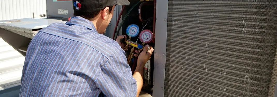 HVAC technician servicing a condenser unit in Riverbank